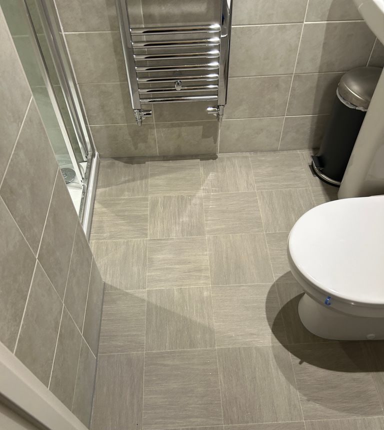 Grey bathroom floor tiling and heated towel rail by Yorkshire Green Heating in Doncaster